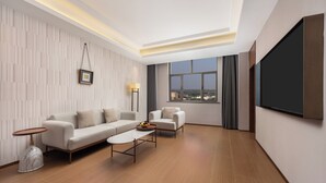 A modern living room with a sofa, armchair, coffee table, and a TV mounted on the wall. - Wanda Moments Neo Qiemo (Qiemo)