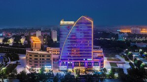 A modern hotel with a distinctive triangular roof and illuminated signage. - Wanda Moments Neo Qiemo (Qiemo)