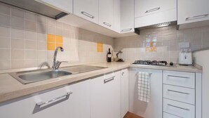 A modern kitchen with white cabinets, a stainless steel sink, and a gas stove. - 10 minutes from the center (Firenze)