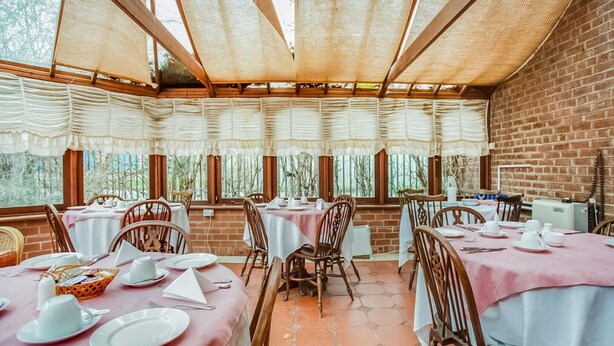 A restaurant with brick walls, large windows, and tables set with white tablecloths and pink table runners. - Standard Double Room (Gateshead)