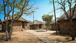 Un village pittoresque avec des huttes aux toits de chaume, des murs de pierre et une place centrale pavée.