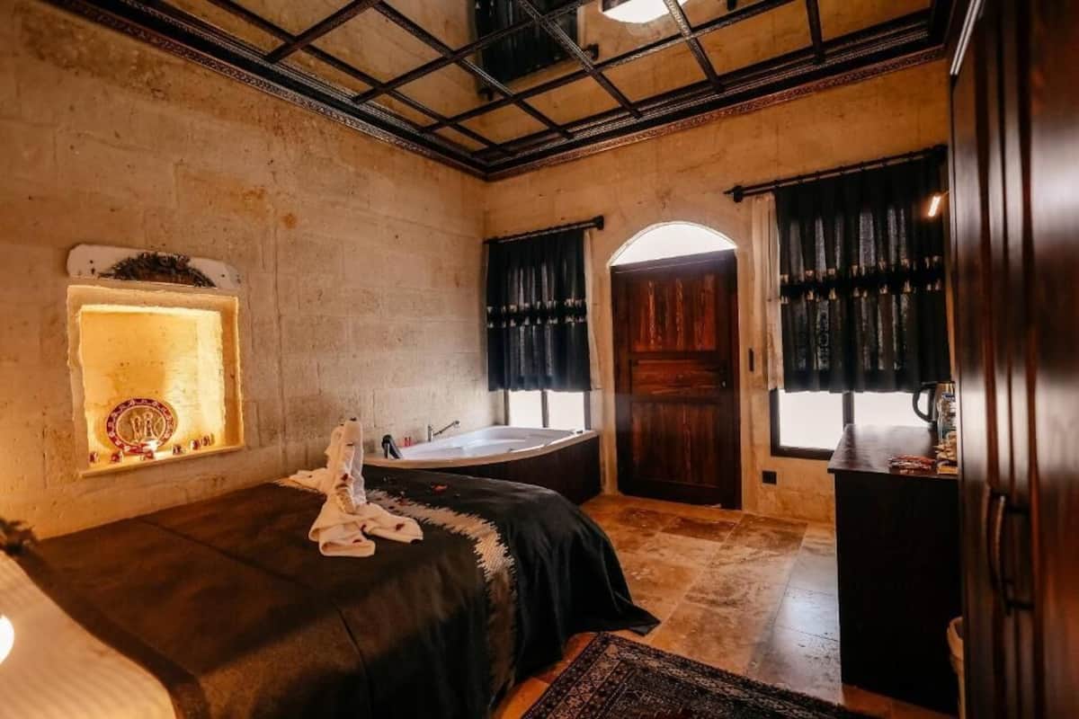 A bedroom with a large bed, a bathtub, and a window with curtains.