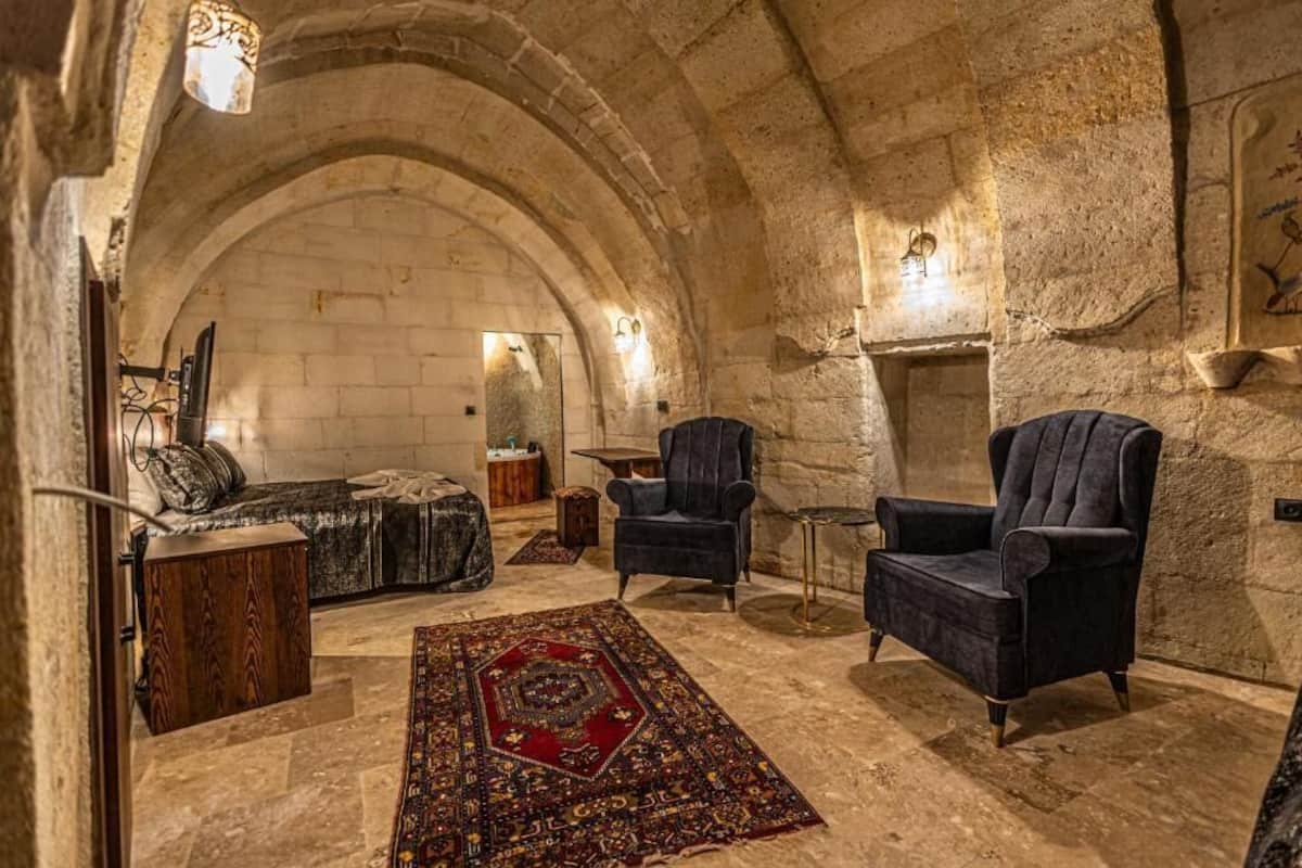 A cozy room with stone walls, a large rug, and two armchairs.