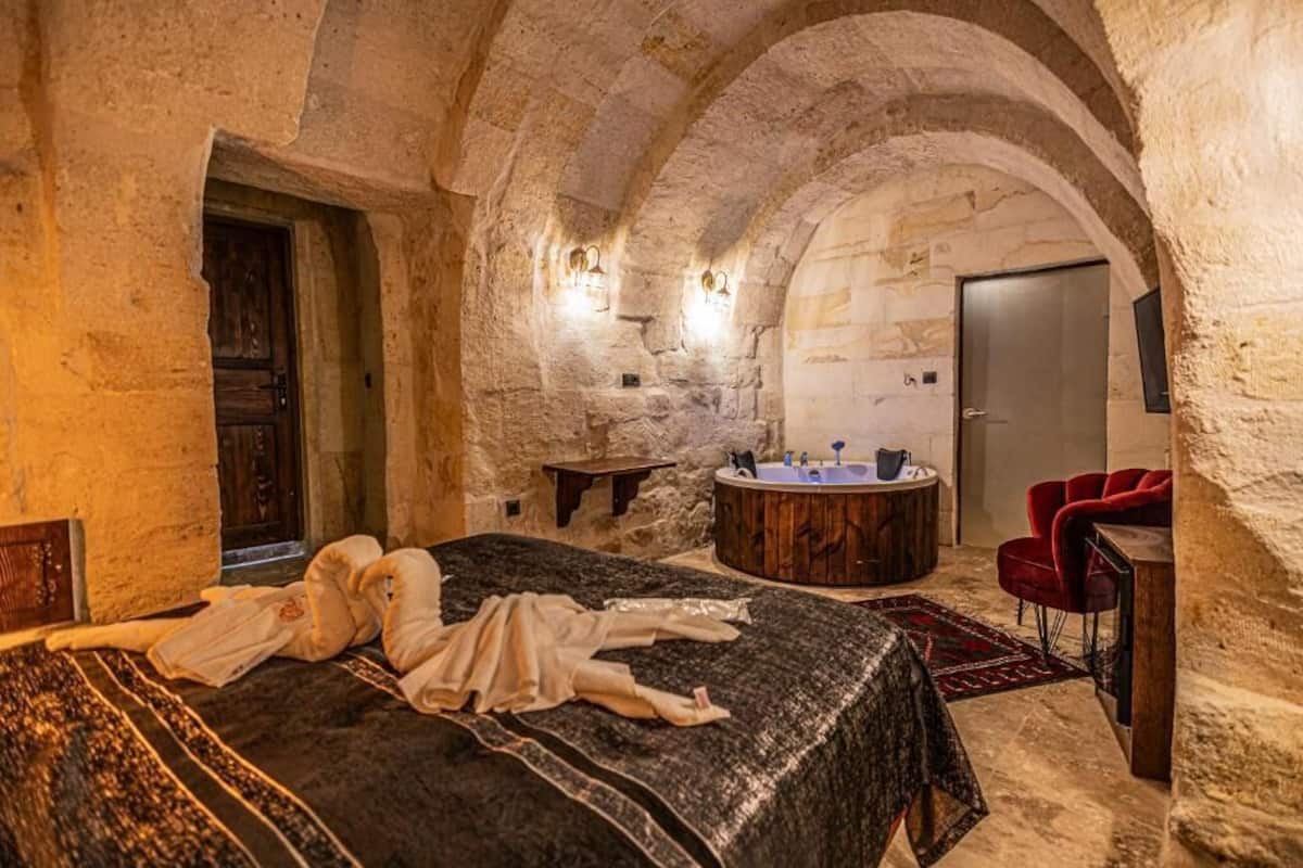 A room with a bed, a wooden bench, a round wooden bathtub, and a red chair.