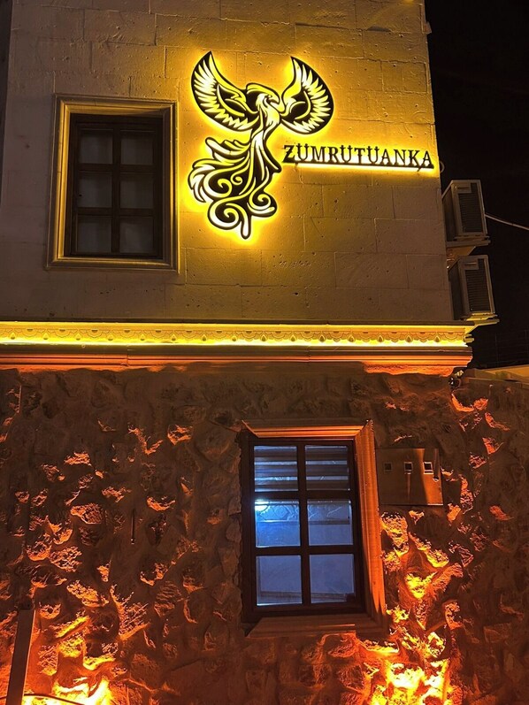 A building with a glowing emblem and the name "ZUMRUTUANKA" on the facade. - Zümrütü Anka Cave (Ürgüp)