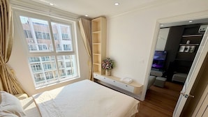 Une chambre d’hôtel avec un grand lit, une coiffeuse avec un miroir, un petit coin salon et une vue sur la ville par la fenêtre.
