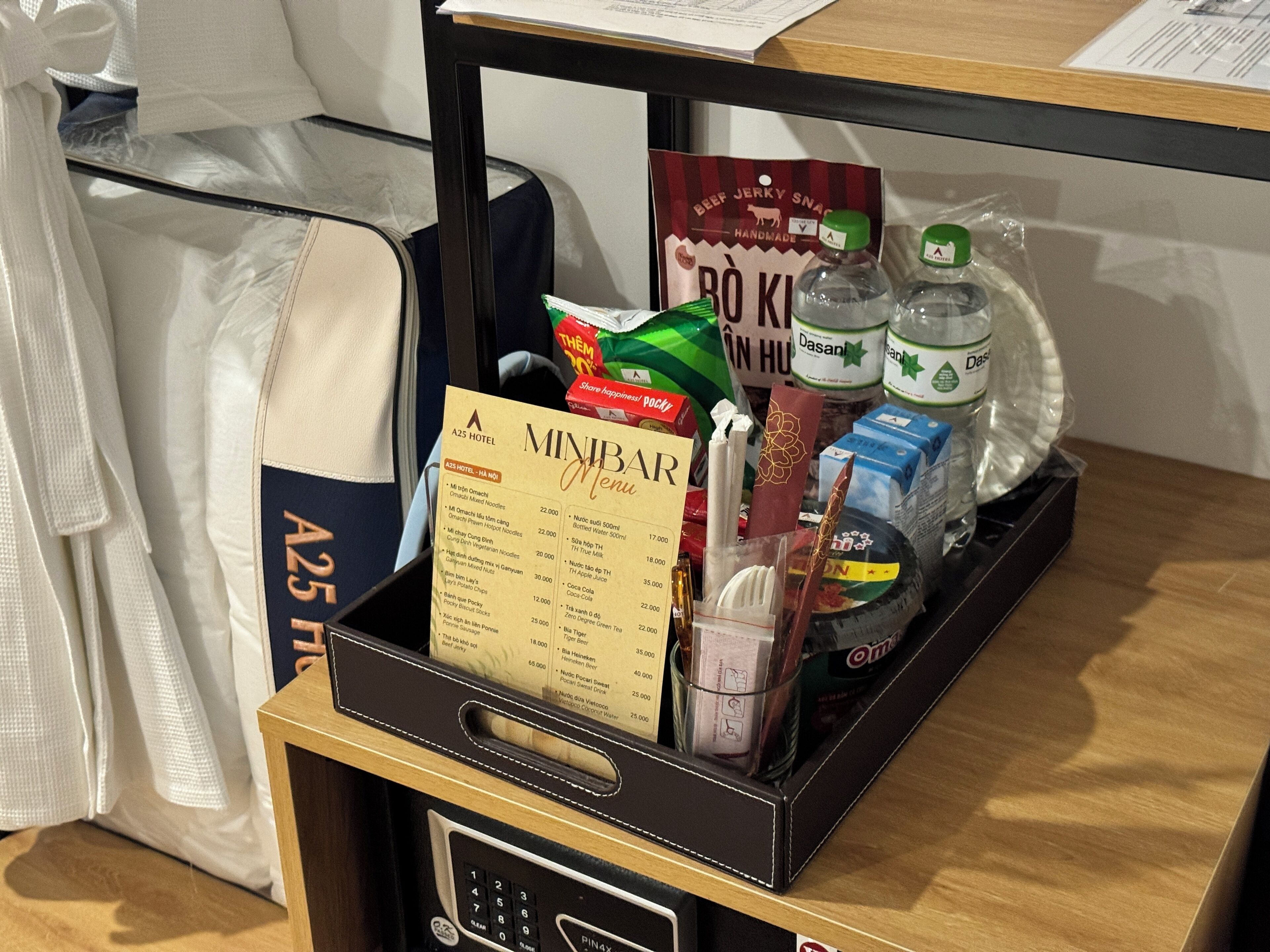 A minibar with a menu, snacks, bottled water, and a bottle of Dasani water.