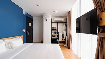 A hotel room with a bed, a TV, a wardrobe, and an air conditioning unit.