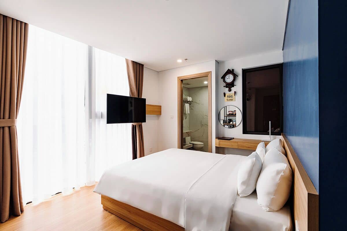Een hotelkamer met een bed, een televisie, een spiegel en een klok aan de muur.