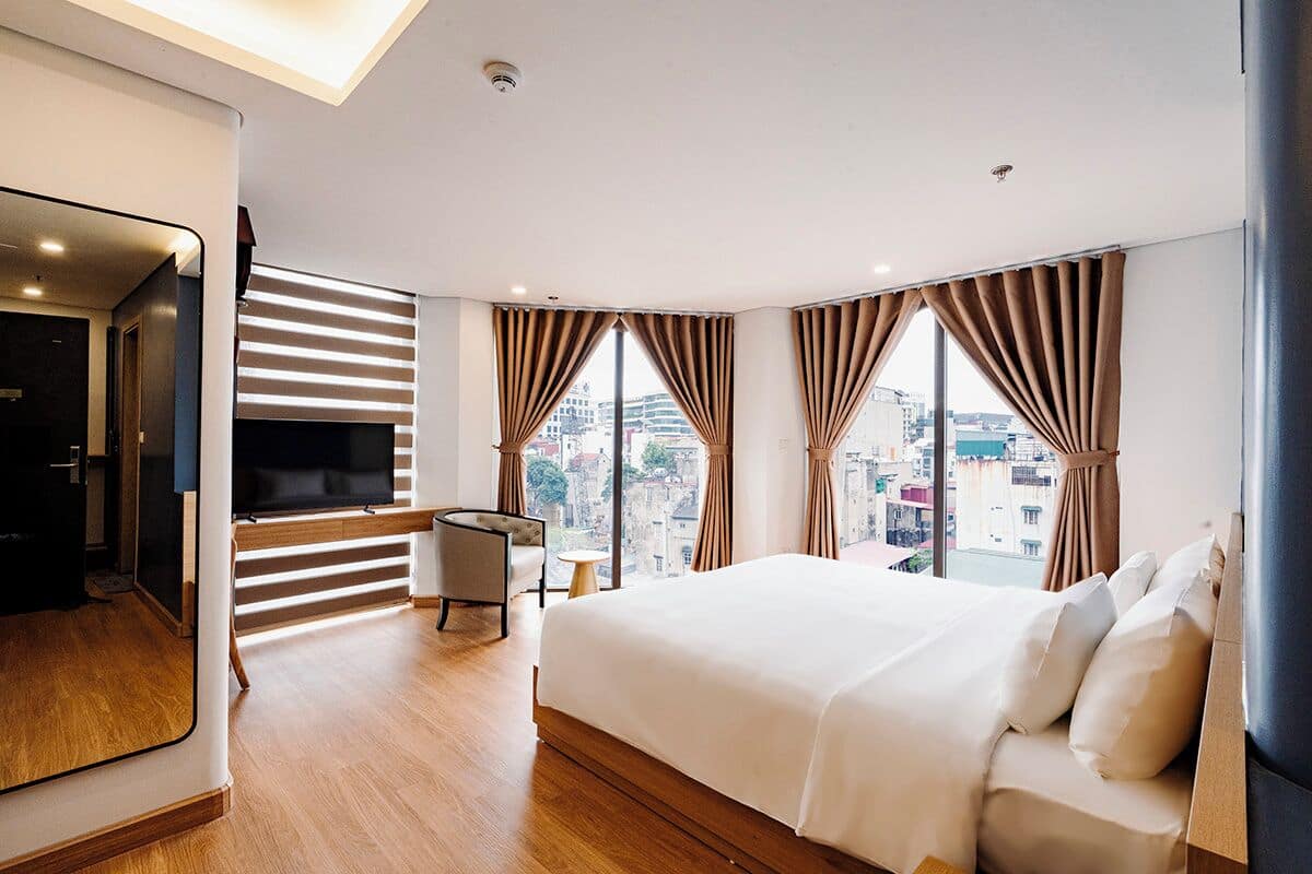 Een moderne hotelkamer met een groot bed, een televisie, een bureau en uitzicht over de stad.