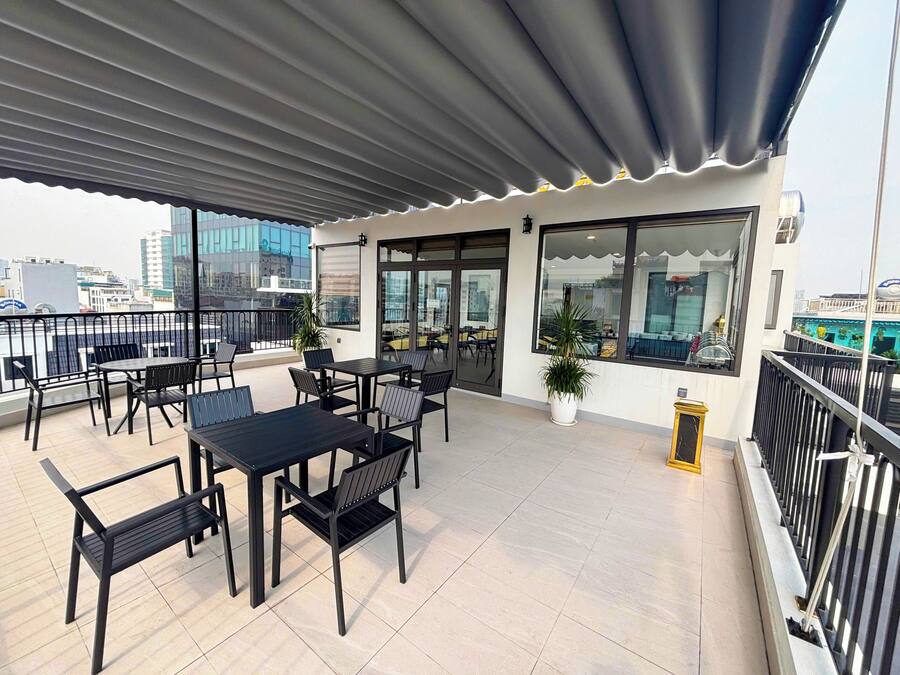 Une terrasse sur le toit, avec des tables et des chaises, un pot de fleurs et une vue sur le paysage urbain.