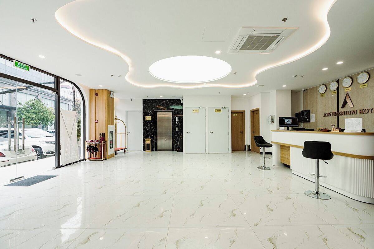 A hotel reception area with a modern design, including a marble floor, a reception desk, and a view of the street outside.