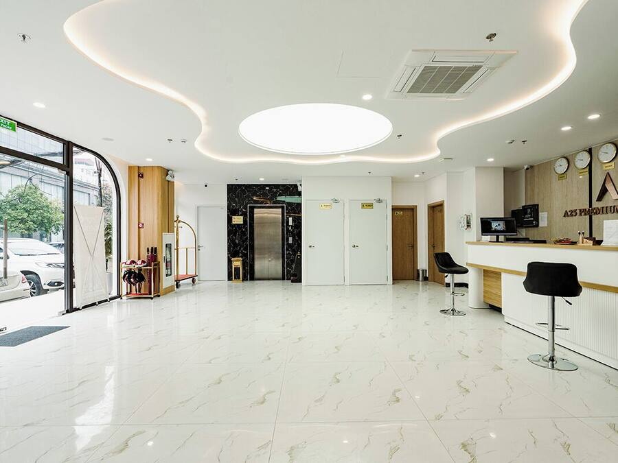 A hotel reception area with a modern design, including a marble floor, a reception desk, and a view of the street outside.