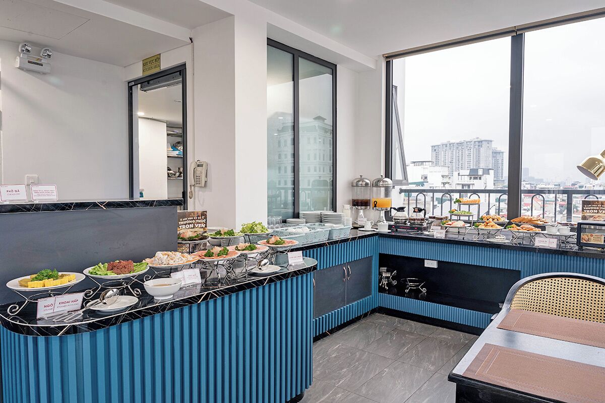 A modern kitchen with a buffet setup, a large window with a city view, and a seating area with a table and chairs.