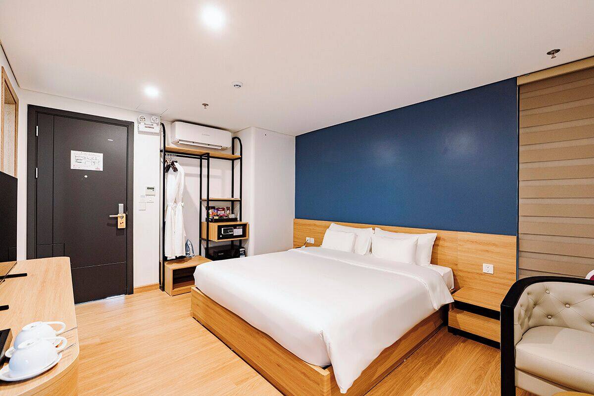 Hotelkamer met een bed, een bureau met stoel, een kledingkast en een wandairconditioning.