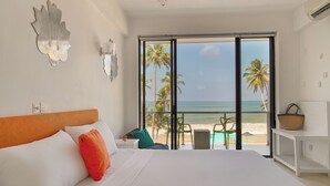 A bedroom with a large bed, a view of the beach, and a balcony with chairs and a table. - Mask & Tide - Jetwing Select (Ambalangoda)