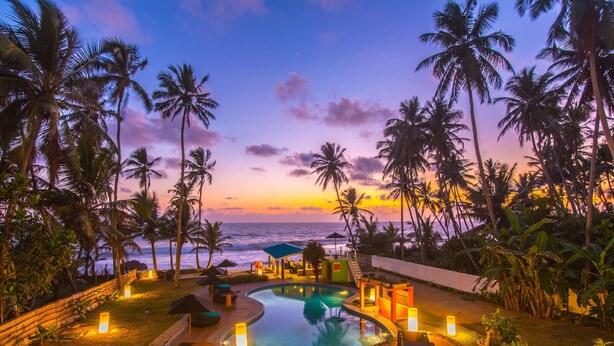 A poolside area with lounge chairs and a view of the ocean at sunset. - Mask & Tide - Jetwing Select (Ambalangoda)