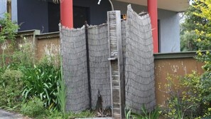 A building with a red column, a wooden fence, and some greenery. - Belong At Bendalong is a large family home (Bendalong)
