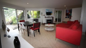 A modern living room with a red sofa, a dining table with chairs, a TV, and a fireplace. - Belong At Bendalong is a large family home (Bendalong)