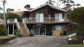 A two-story house with a balcony, a covered driveway, and a sign that reads 'BANYAN'. - Belong At Bendalong is a large family home (Bendalong)