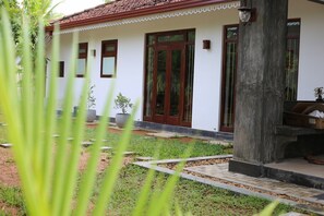 A white building with a red-tiled roof, large glass doors, and potted plants in the foreground. - Luxury Type 3-bedroom villa in perfect Unawatuna with cool AC comfort (Unawatuna)