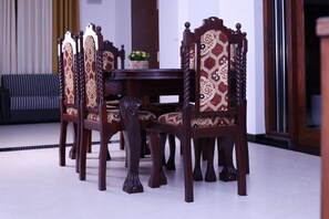 A dining area with a round table surrounded by six wooden chairs with intricate back designs. - Luxury Type 3-bedroom villa in perfect Unawatuna with cool AC comfort (Unawatuna)