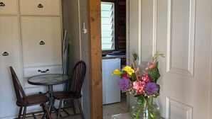 A kitchen with a dining table and chairs, a refrigerator, and a vase with flowers on the counter. - "The Valley " Studio Kentucky. Set on a quiet country rd  with a divine outlook. (Kentucky)