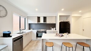 Cozinha moderna com ilha central, eletrodomésticos de aço inoxidável e parede de tijolos.