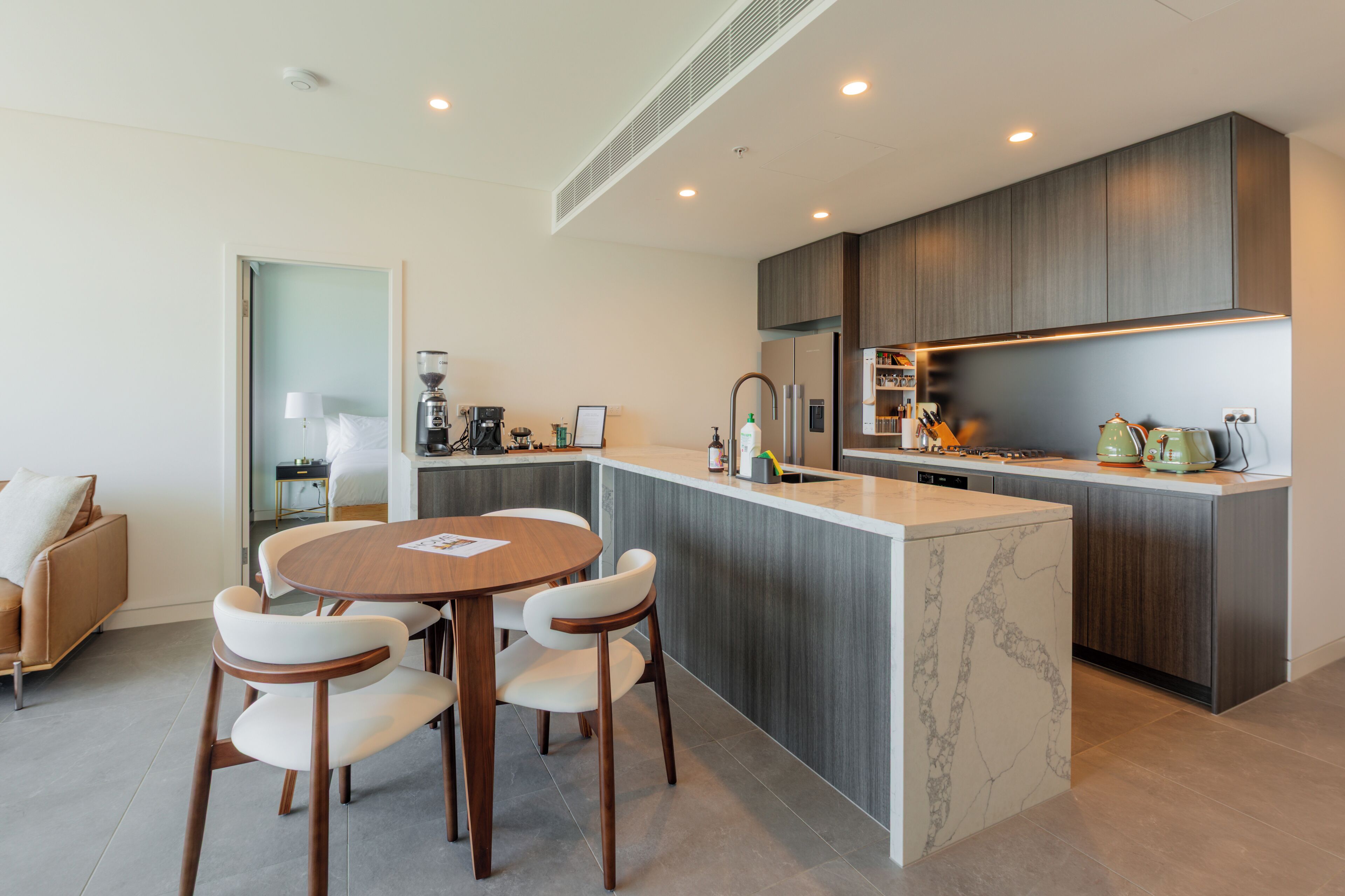 A modern kitchen with a central island, built-in appliances, and a dining area with a round table and chairs.