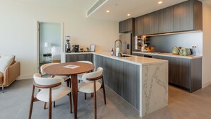Uma cozinha moderna com ilha central, eletrodomésticos embutidos e área de jantar com mesa redonda e cadeiras.
