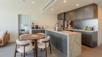 A modern kitchen with a central island, built-in appliances, and a dining area with a round table and chairs.