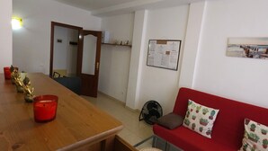 A living room with a wooden table, red sofa, and a fan. - Charming Holiday House in Las Palmas with City Views (Telde)