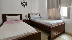 A room with two wooden beds, a bedside table with a lamp, a framed artwork on the wall, and a window with curtains. - Charming Holiday House in Las Palmas with City Views (Telde)