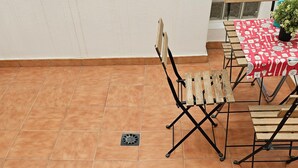 A patio with terracotta tiles, a welcome mat, and a table with a red tablecloth. - Charming Holiday House in Las Palmas with City Views (Telde)