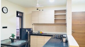 Una cocina moderna con encimera negra, armarios de madera, estufa y ventilador de techo.