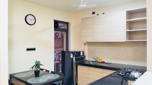 Una cocina compacta con comedor, ventilador de techo y un reloj en la pared.