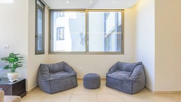 A modern living room with two grey sofas, a small ottoman, and a potted plant.