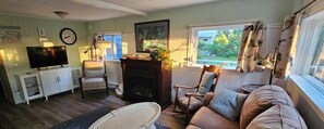 A living room with a fireplace, a television, a sofa, and a window with curtains.