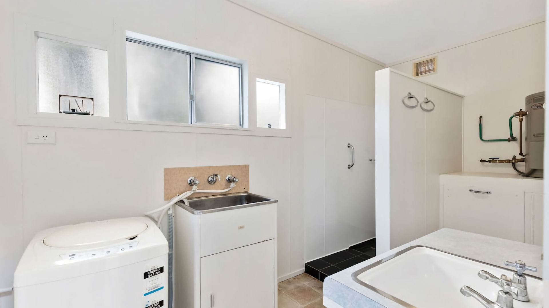 A compact bathroom with a washing machine, a sink, and a toilet.
