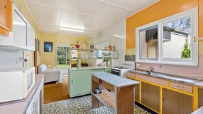 A compact kitchen with a built-in stove, a sink, and a window. - Elanora is an original cottage (Bendalong)