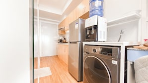 A compact kitchen with a stainless steel refrigerator, a built-in oven, a water dispenser, and a washing machine. - Verdon Parc Davao City Condo - Perfect Staycation Near SM Ecoland (Davao City)