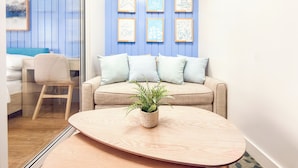A modern room with a blue wall, a beige sofa, and a wooden coffee table with a plant. - Verdon Parc Davao City Condo - Perfect Staycation Near SM Ecoland (Davao City)