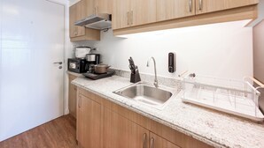 A modern kitchen with wooden cabinets, a stainless steel sink, and a coffee maker. - Verdon Parc Davao City Condo - Perfect Staycation Near SM Ecoland (Davao City)