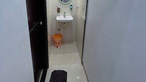 Un corridoio stretto che porta a un bagno con lavandino, specchio e water.