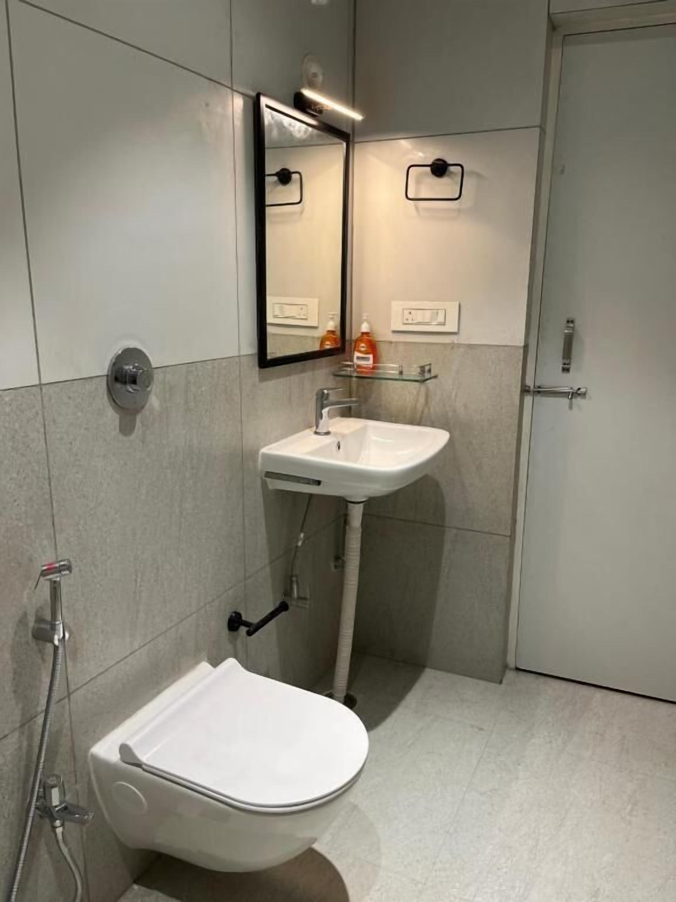 A modern bathroom with a white sink, a mirror, and a toilet.