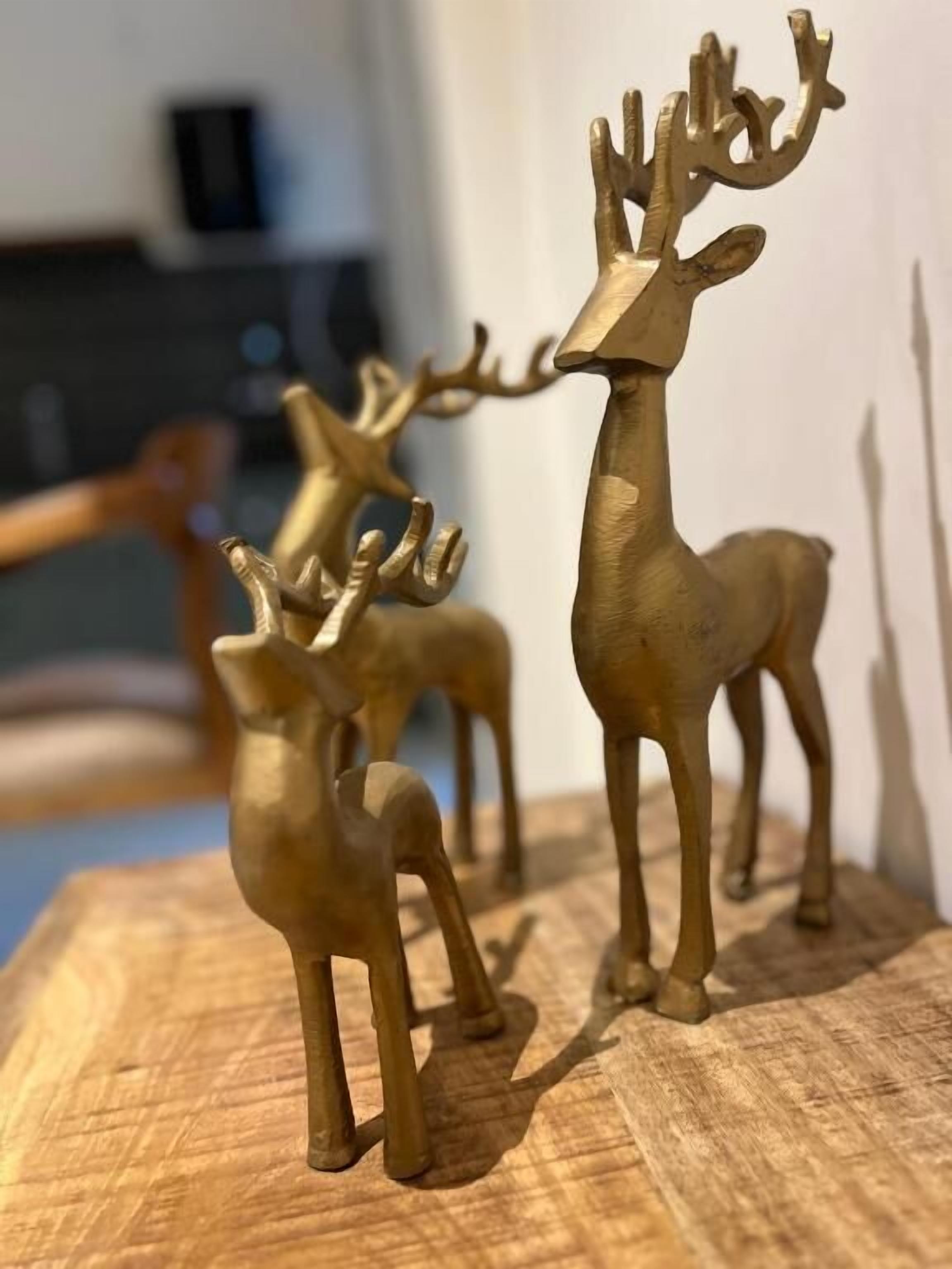 A wooden table with three golden deer figurines.