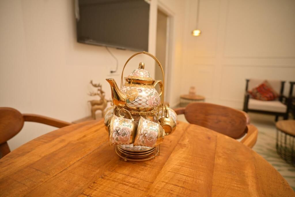 Una mesa redonda de madera con una tetera dorada decorativa y tazas.