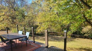 Une terrasse extérieure avec une table et des chaises, entourée d’une clôture en bois et d’arbres.