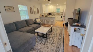 Un salon moderne avec un canapé gris, une table basse et un tapis à motifs.