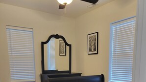 Une chambre à coucher avec un lit, une commode, un miroir et une petite table ronde.